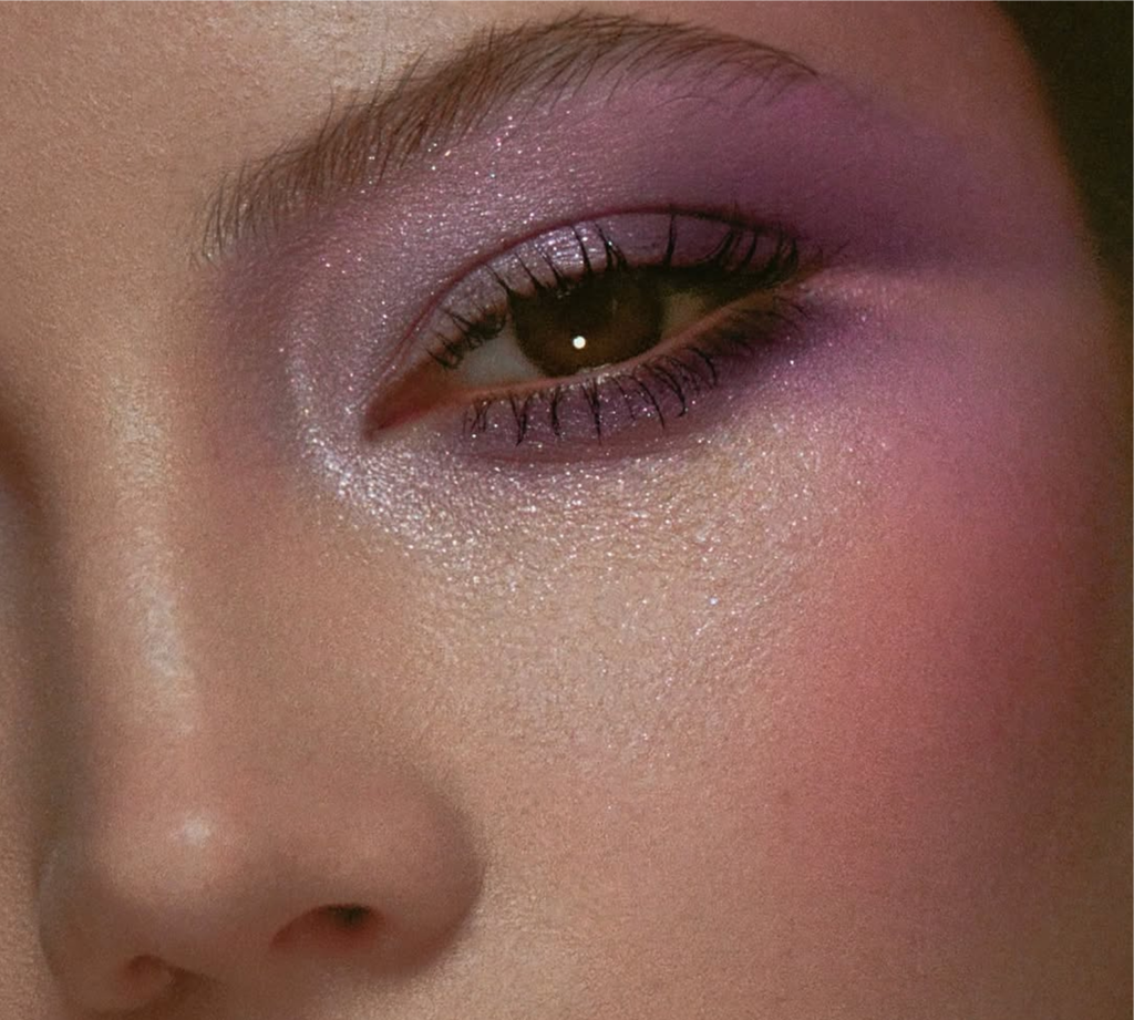 Maquillaje por Raoul Alejandre en tonos lila y rosa suave con piel luminosa, que muestra el regreso del color y el brillo al maquillaje tras el clean girl look.