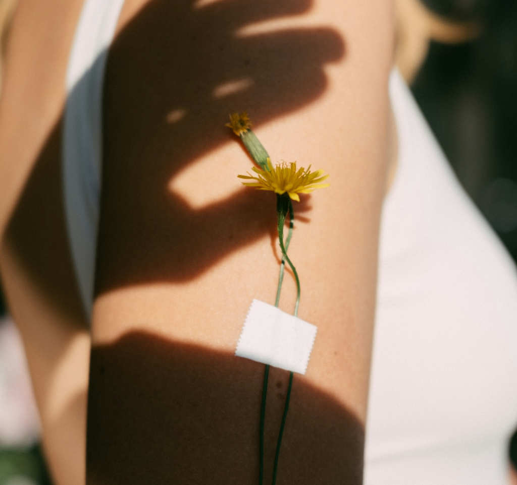 Brazo con flor amarilla sostenida por cinta bajo luz y sombra representando fragilidad y cuidado en endometriosis síntomas diagnóstico